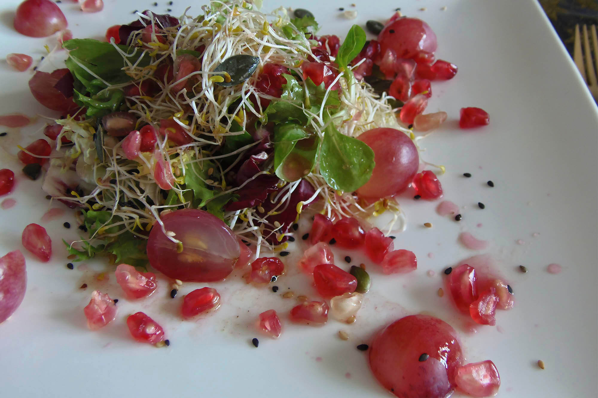 Ensalada de granada y uvas con brotes
