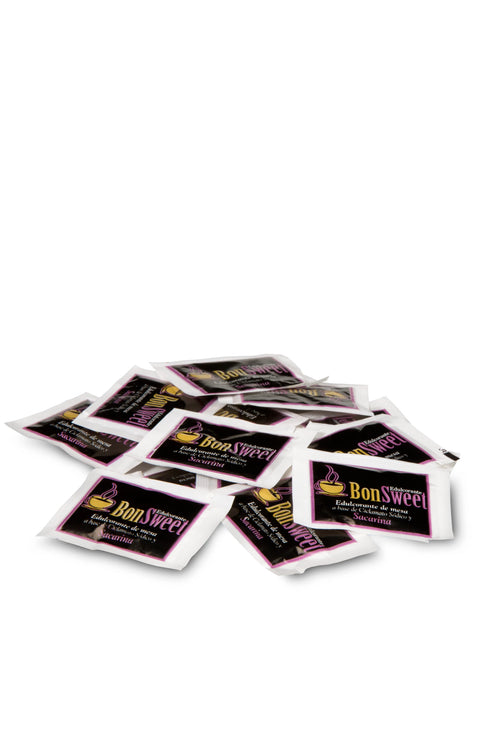 Montón de sobres individuales de edulcorante BonSweet Sacarina sobre fondo blanco, ideales como sustituto del azúcar en hostelería y cafeterías para endulzar de forma rápida café, té o infusiones.