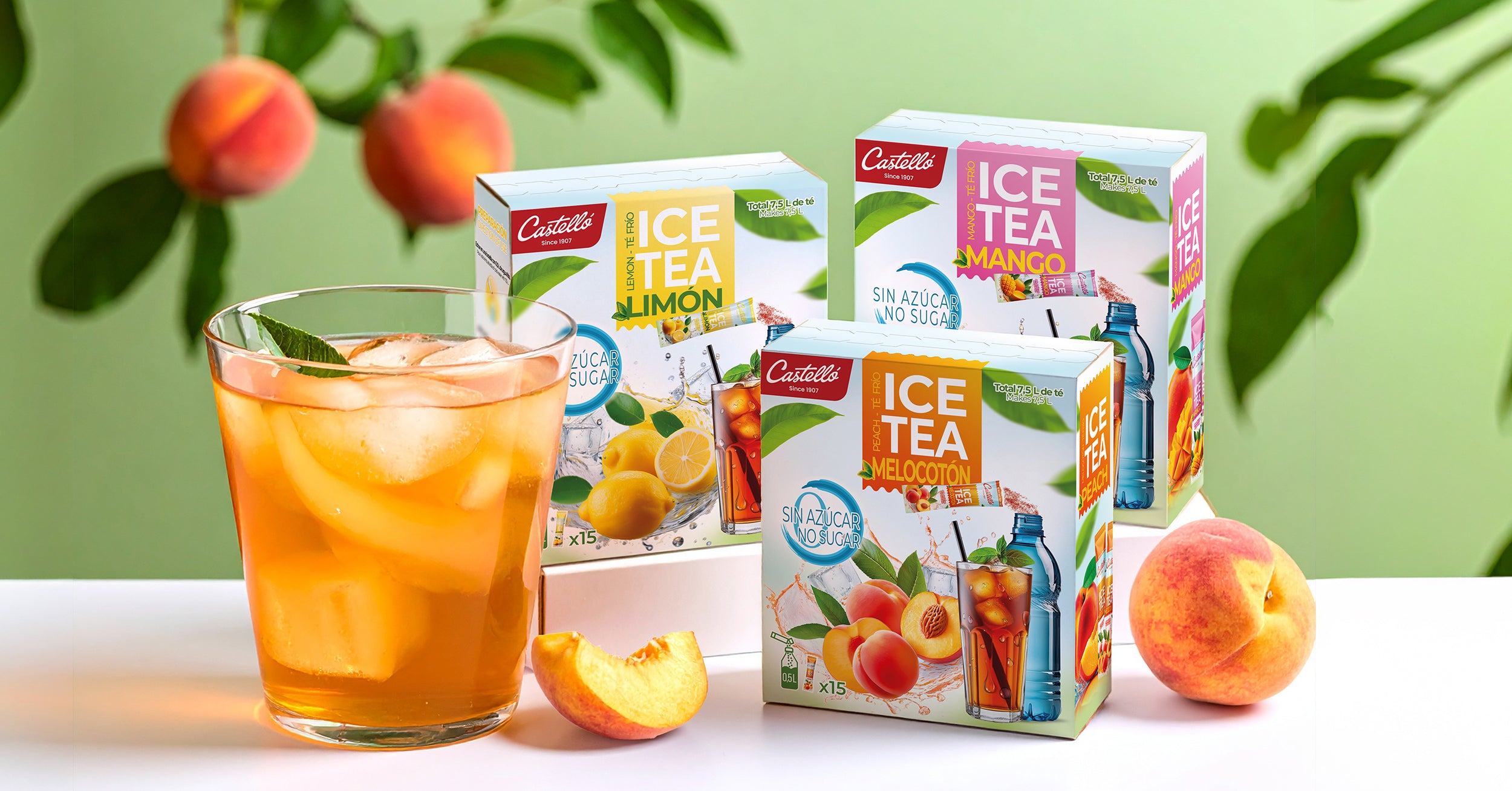 Cajas de tés fríos sin azúcar Castelló sabores limón, mango y melocotón junto a un vaso de té con hielo.